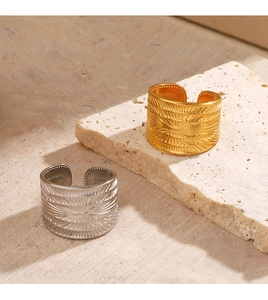 Détail de bagues larges ondulées plaquées or 18 carats et argent sur texture pierre