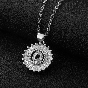 Détail macro du pendentif lettre Q argenté serti de zircons sur une chaîne en acier