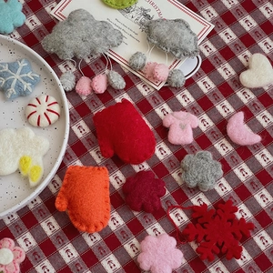 Flat lay of colorful wool felt Christmas DIY charms like stars and clouds on red plaid cloth