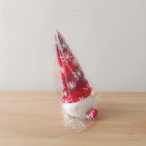 Close-up of Christmas gnome toy with knit snowflake hat in clear plastic packaging