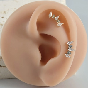 Macro view of gold and silver G23 titanium crown ear studs with sparkling cubic zirconia