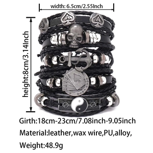 Detail view of multilayer leather bracelet set with skull and anchor charms on white background
