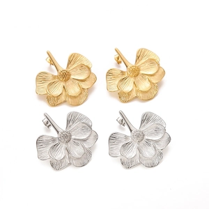 Detailed close-up of textured gold and silver floral earrings with layered petals