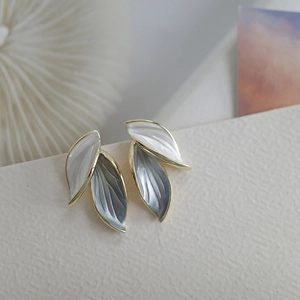 Detailed macro view of leaf shaped enamel earrings with gold trim and gradient finish