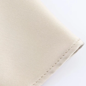 Gros plan détaillé du tissu en satin beige montrant des coutures fines et une texture lisse