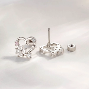 Silver hollow heart flower stud earrings with white and pink zircon on white silk background