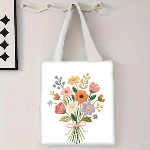 Détail de la broderie florale colorée sur un sac cabas en toile blanche suspendu