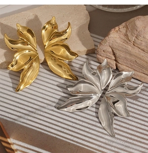 Macro shot of abstract metal flower petal earrings in gold and silver on natural stone