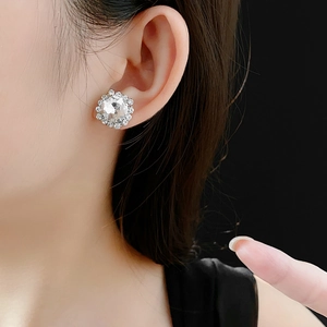 Close-up of a silver cubic zirconia stud earring worn on a model against a black background