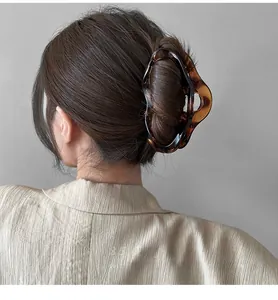 Detail view of a large tortoiseshell hair claw clip securing a thick bun in a stylish updo