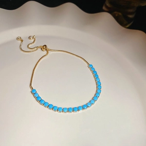 Detail of adjustable gold crystal bracelet featuring sky blue circular stones and slider clasp