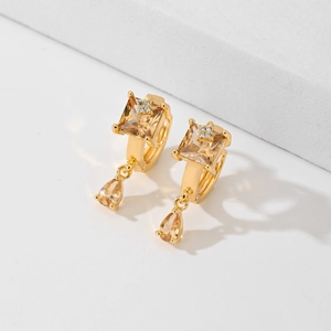 Elegant gold earrings with square stones and pear-shaped drops on white background