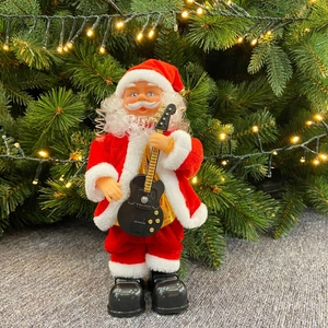 Electric musical Santa Claus toy with black guitar standing by a Christmas tree