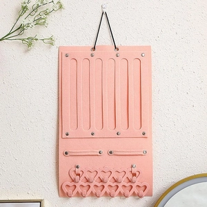 Pink felt wall jewelry organizer featuring heart-shaped hooks and earring slots
