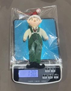 Christmas elf plush ornament in packaging being weighed on a digital scale, 13.0g total