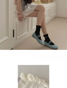 Close-up of white crew socks featuring ruffled edges and delicate heart embroidery detail