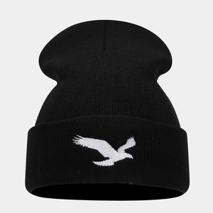 Detailed close-up of white eagle embroidery on a black ribbed knit beanie hat