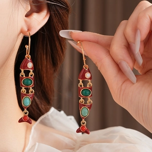 Gros plan détaillé de boucles d'oreilles poisson vintage avec émail rouge et gemmes