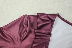 Detail of burgundy satin dress showing ruffled edges and smooth silk texture