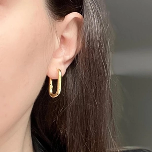 Minimalist 18k gold plated stainless steel U-shaped hoop earrings worn by a model