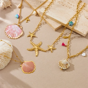 Detail shot of four gold necklaces featuring sea shell, starfish and ocean charms on stones