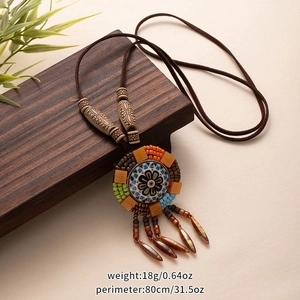Detail of bohemian necklace with colorful round pendant, tassels and wooden beads