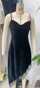 Détail de la robe en velours noir montrant de la dentelle et un ourlet asymétrique