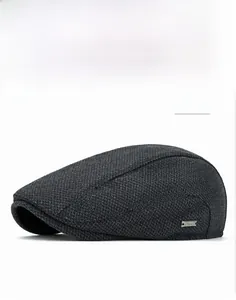 Close-up of dark grey tweed newsboy cap with textured weave and metal side badge