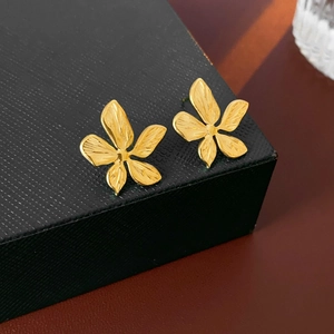 Macro shot of gold flower earrings with metallic texture on a black jewelry box