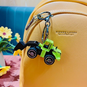 Mini green excavator construction truck keychain accessory on a yellow backpack bag
