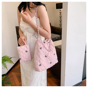 Detail of pink quilted tote with black bows, chain strap and matching coin purse