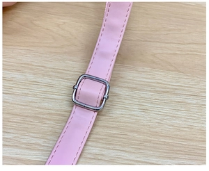 Gros plan sur la bandoulière réglable en similicuir rose avec boucle en métal argenté