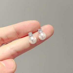 Close-up of elegant silver earrings featuring square zircon studs and round white pearls