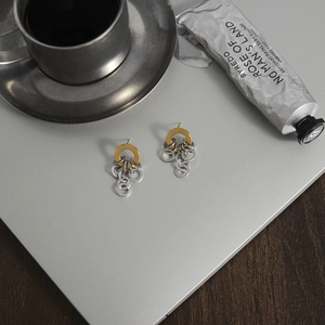 Boucles d'oreilles minimalistes bicolores en acier 18K sur surface métallique