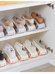 Detail view of adjustable double-layer plastic shoe organizers in a white wooden cabinet