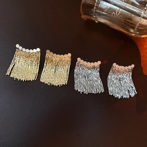 Detail view of gold and silver tassel chain earrings with sleek metallic finish