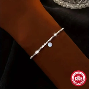 S925 sterling silver chain bracelet with round opal stone pendant on a woman's wrist