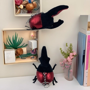 Detail of creative beetle plush keychain in metallic red and black with metal ring