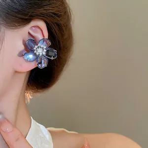 Elegant blue flower clip-on earring with zircon center on model in warm grey background