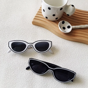 Retro cat-eye sunglasses with contrasting frame lines on a textured stone surface
