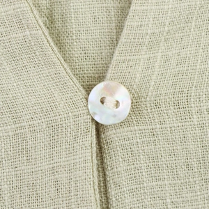 Detail of light green linen fabric with a pearlescent mother-of-pearl button on dress