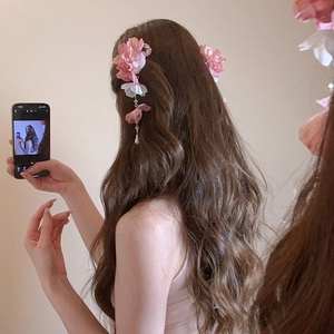 Détail d'une pince à cheveux fleur en soie rose avec long pompon et perles sur un mannequin