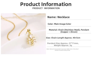 Macro detail of gold cedar leaf pendant with zircon inlay and stainless steel chain