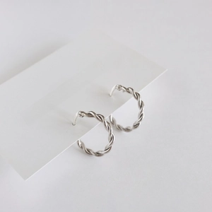 Detail of silver twisted hoop earrings displayed on a minimalist jewelry card background