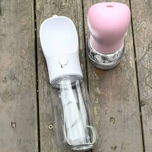 Overhead view of pink and white portable pet water bottles on dark wood floor