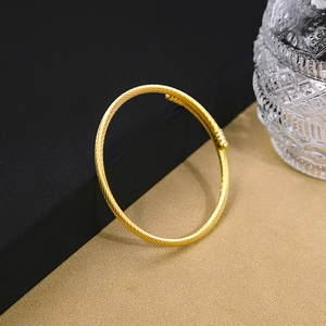 Detail of a golden twisted cable open bangle with polished spherical end caps
