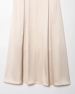 Gros plan d'une jupe mi-longue en satin champagne montrant le drapé et la texture soie
