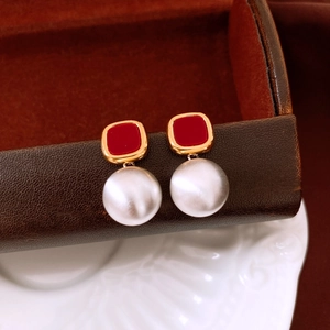 Detail view of vintage matte gold pearl earrings with red resin on jewelry box