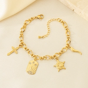 Detail of gold-tone cross, star, and moon charms on a stainless steel O-chain bracelet