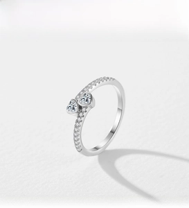 Detailed macro view of silver ring featuring two heart shaped zircons and pavé diamonds